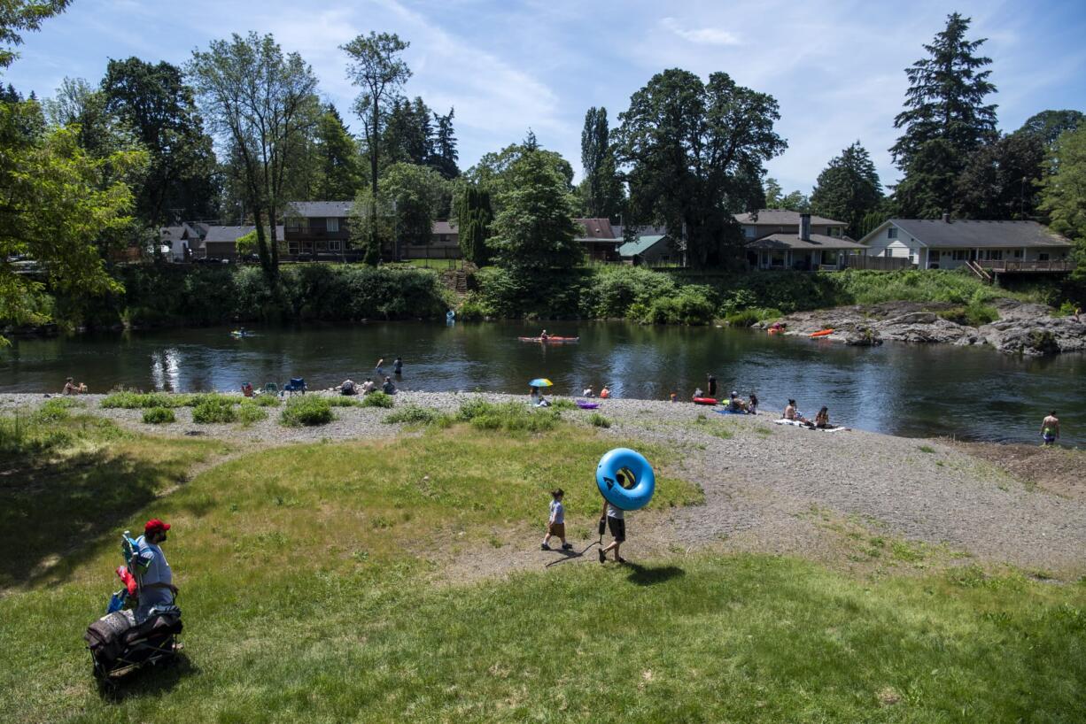 People line the beach on the first day of official reopening at Sandy Swimming Hole Park in Washougal on Friday. The park has been closed due to the COVID-19 public health emergency.