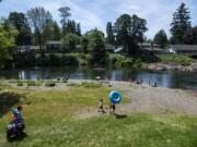 People line the beach on the first day of official reopening at Sandy Swimming Hole Park in Washougal on Friday. The park has been closed due to the COVID-19 public health emergency.