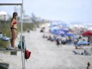 Kure Beach Ocean Rescue lifeguard Katy Kelly looks out from a stand at Kure Beach, N.C., Saturday, May 23, 2020. The town lifted the majority of beach restrictions related to the coronavirus on May 15.