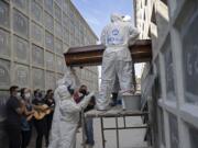 The family of Carmen Valeria watch her remains as they are placed into a niche Thursday at the Iraja cemetery in Rio de Janeiro, Brazil. The family suspects the 76-year-old died from COVID-19.