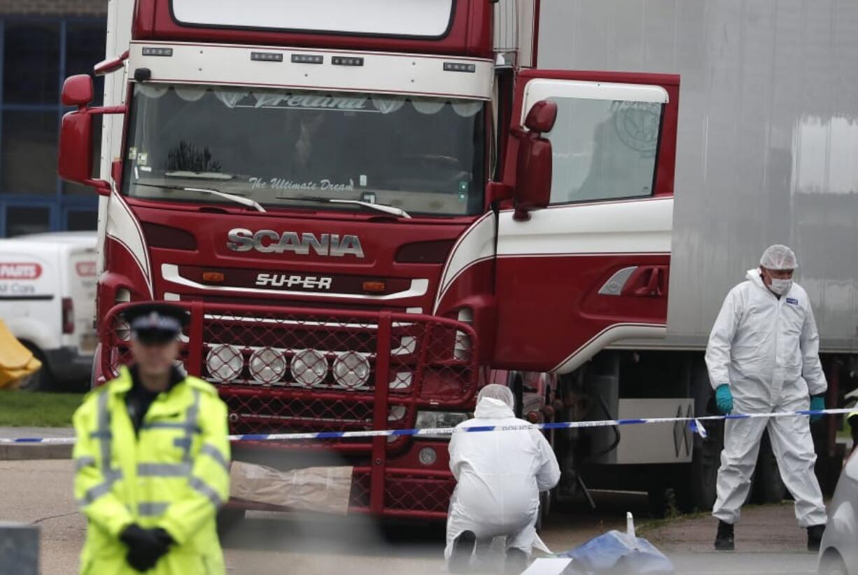 FILE - In this Wednesday Oct. 23, 2019 file photo, forensic police officers attend the scene after a truck was found to contain a large number of dead bodies, in Grays, South England. Police have arrested 26 people suspected of human trafficking during a large-scale operation in Belgium and France in relation to the death of the Vietnamese migrants whose bodies were found in a refrigerated truck in Britain last year.