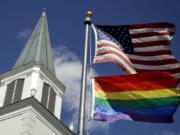 A gay pride rainbow flag flies along with the U.S. flag April 19, 2019, in front of the Asbury United Methodist Church in Prairie Village, Kan. Had there been no COVID-19 coronavirus pandemic, America&#039;s largest mainline Protestant denomination would be convening in May.