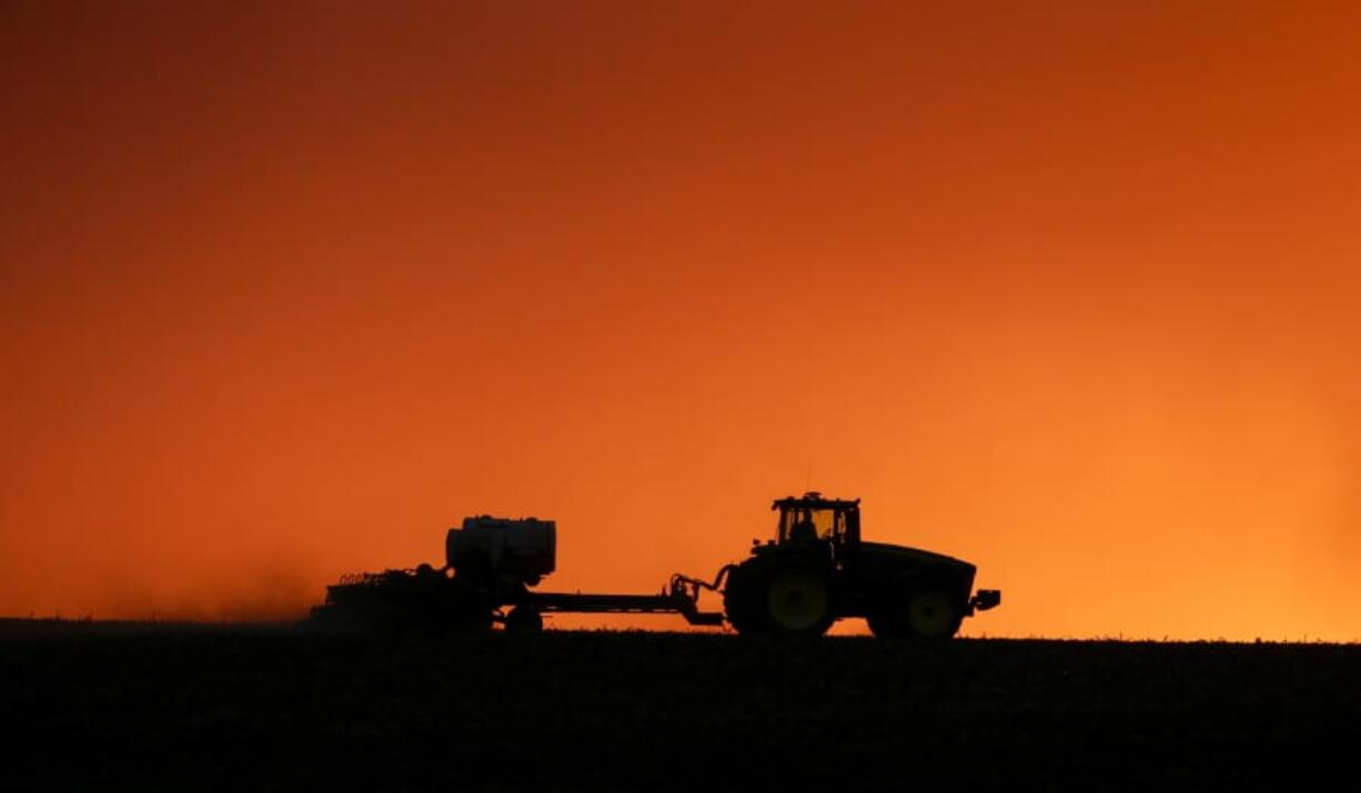 FILE - In this April 20, 2020, file photo, a farmer is silhouetted by the setting sun as a field is planted near Walford, Iowa. U.S. farmers across the nation leaned more heavily upon the federal government last year to finance their agricultural operations amid low commodity prices and trade disputes, and more of the money they borrowed from taxpayers is now delinquent.