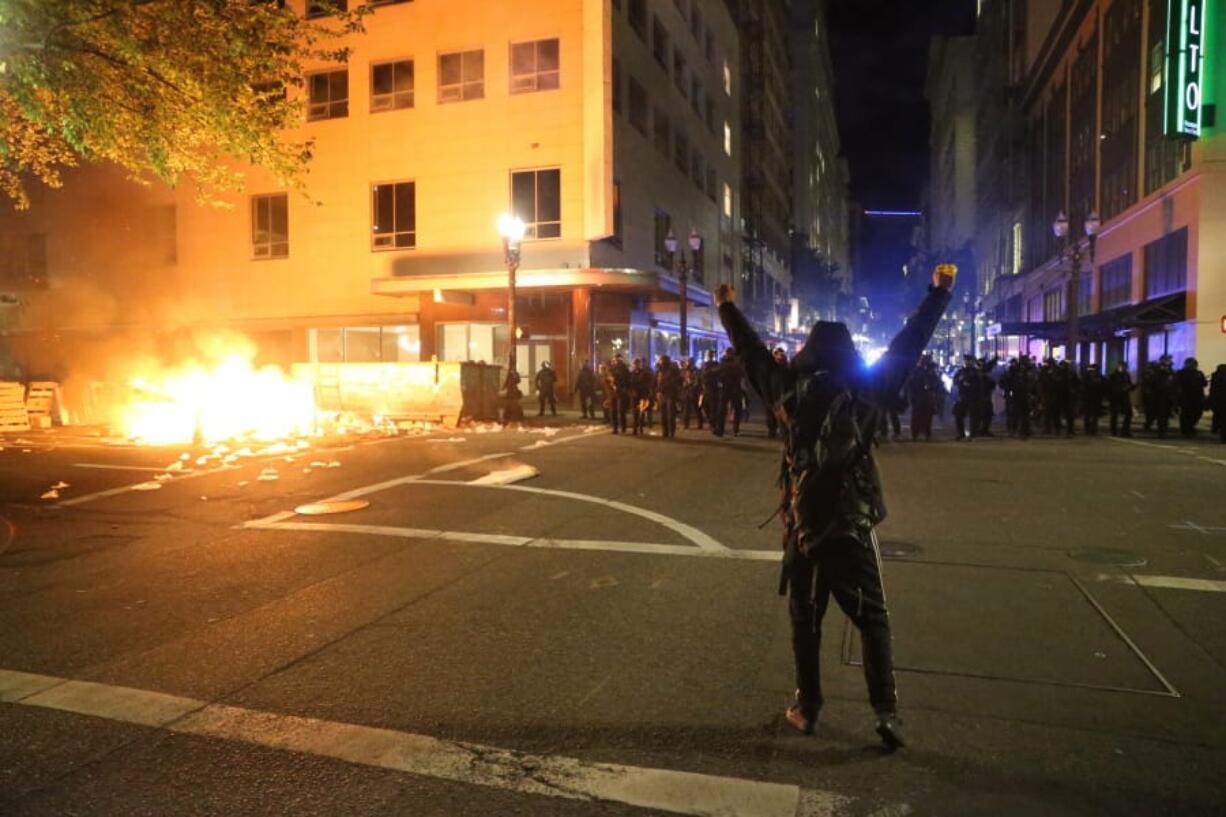 A protestor faces police officers in downtown in Portland, Friday.