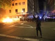 A protestor faces police officers in downtown in Portland, Friday.