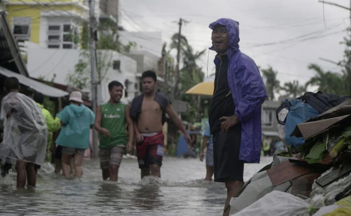 Residents wade along a flooded village caused by typhoon Vongfong as it passed by Sorsogon province, eastern Philippines on Friday May 15, 2020. More than 150,000 people were riding out a weakening typhoon in emergency shelters in the Philippines on Friday after a mass evacuation that was complicated and slowed by the coronavirus.