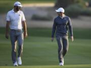 FILE - In this Jan. 18, 2018, file photo, Dustin Johnson of the United States, left, and Rory McIlroy of Northern Ireland talk on the 10th fairway during the first round of the Abu Dhabi Championship golf tournament in Abu Dhabi, United Arab Emirates. Dustin Johnson left The Players Championship two months ago and didn&#039;t play golf again until Sunday. He figured his game needed to be in shape for Rory McIlroy, his partner, in a charity match Sunday at Seminole that will be live golf&#039;s return to television.