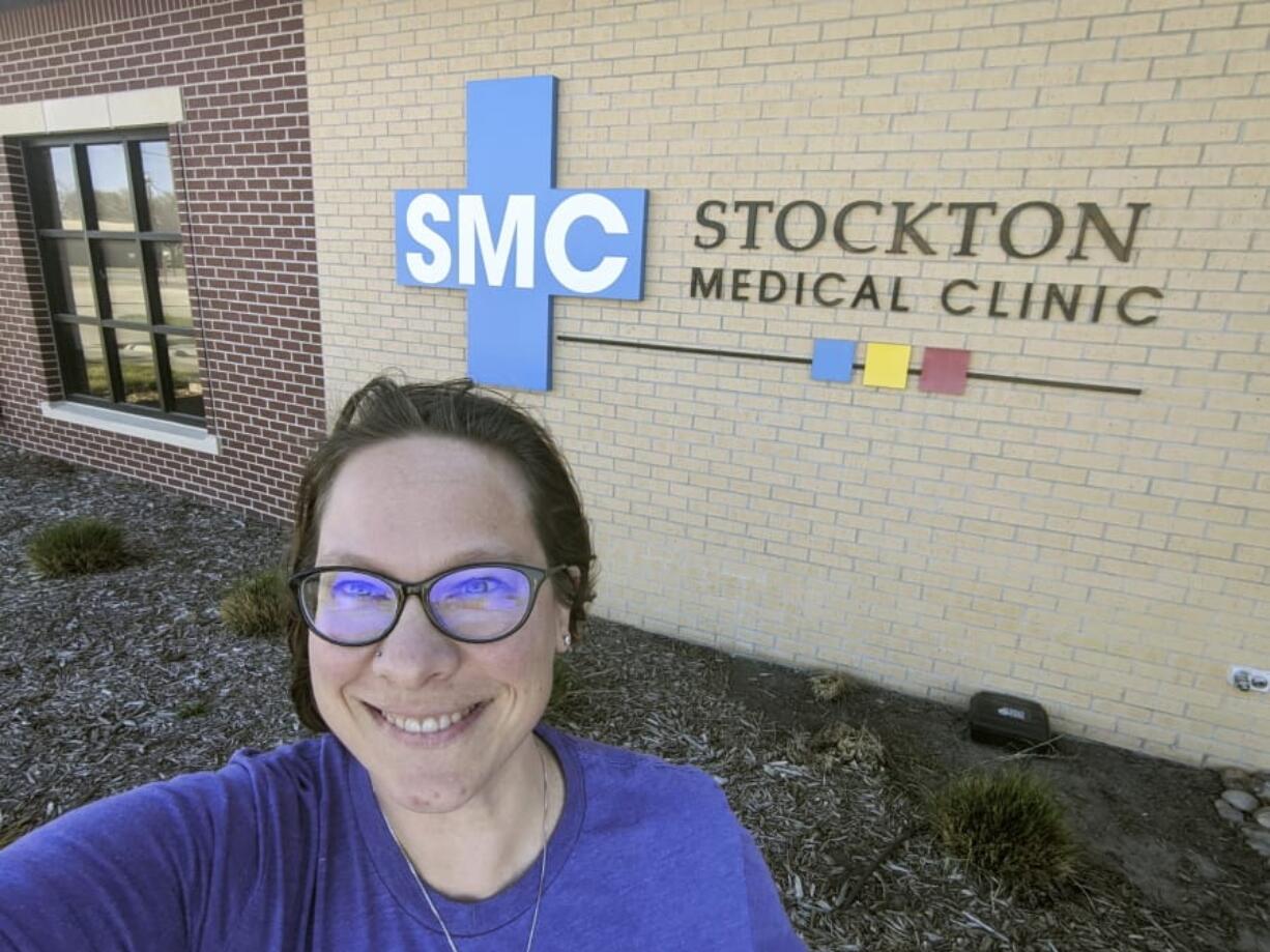 In this Wednesday, April 29, 2020 photo selfie provided by Dr. Beth Oller, Oller, a family physician, smiles while standing outside her medical clinic, just south of Main Street in Stockton, Kan. Oller began preaching social distancing well before her home of Rooks County confirmed its first coronavirus case and now she&#039;s nervous about the state reopening its economy too soon. (Dr.