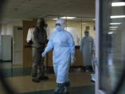 A serviceman of Belarus Ministry of Defence, left, and medical workers wearing protective gear are seen at a local hospital in Minsk, Belarus, Tuesday, May 5, 2020. Despite the World Health Organization&#039;s call for Belarus to ban public events as coronavirus cases rise sharply, President Alexander Lukashenko says the country will go ahead with a parade to mark the 75th anniversary of the defeat of Nazi Germany.