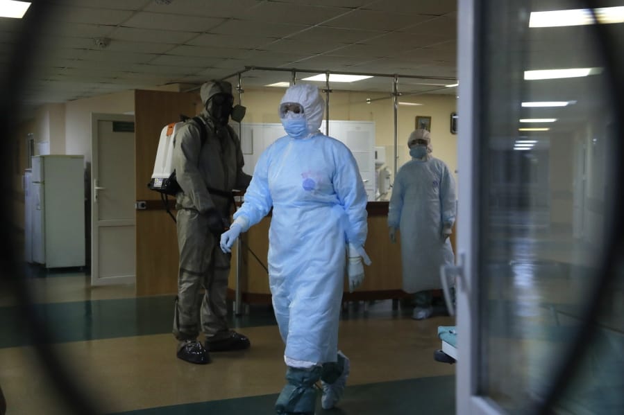 A serviceman of Belarus Ministry of Defence, left, and medical workers wearing protective gear are seen at a local hospital in Minsk, Belarus, Tuesday, May 5, 2020. Despite the World Health Organization&#039;s call for Belarus to ban public events as coronavirus cases rise sharply, President Alexander Lukashenko says the country will go ahead with a parade to mark the 75th anniversary of the defeat of Nazi Germany.