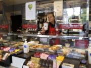 A barista serves from behind protective screens in a Pret coffee shop in London, Thursday, May 14, 2020, as the country continues in lockdown to help stop the spread of coronavirus, Some of the coronavirus lockdown measures are being relaxed in England, with coffee shops reopening but with extra measures such as take away only and social distancing.