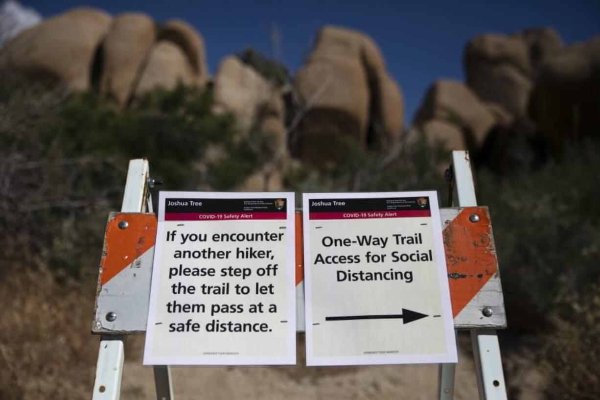 Signs advise visitors to social distance at Joshua Tree National Park in California, Tuesday, May 19, 2020. The park reopened this week after a lengthy closure to help slow the spread of the new coronavirus. (AP Photo/Jae C.