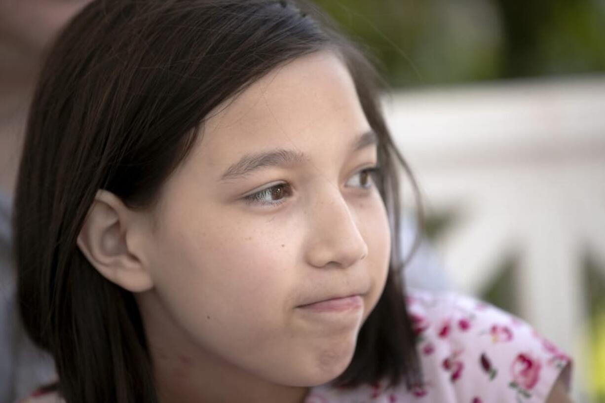 Juliet Daly, 12, sits with her parents on the front porch of their family home in Covington, La., Thursday, April 30, 2020. A team of pediatric cardiology specialists found that Juliet had acute fulminant myocarditis (AFM), an uncommon heart condition that tends to present with sudden onset acute heart failure, cardiogenic shock or life-threatening arrhythmias. A nasal swab confirmed that Juliet was also COVID-19 positive and that she had a second viral infection - adenovirus.