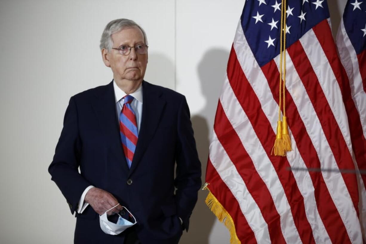 Senate Majority Leader Mitch McConnell of Ky., holds a face mask used to protect against the spread of the new coronavirus as he attends a news conference on Capitol Hill in Washington, Tuesday, May 12, 2020.