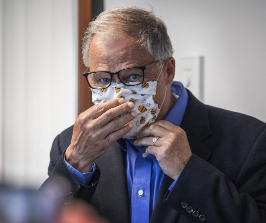 Washington Gov. Jay Inslee puts on his face mask after speaking to the media, Wednesday, May 20, 2020, in Tumwater, Wash., about the state&#039;s effort at contact tracing amid the coronavirus pandemic.