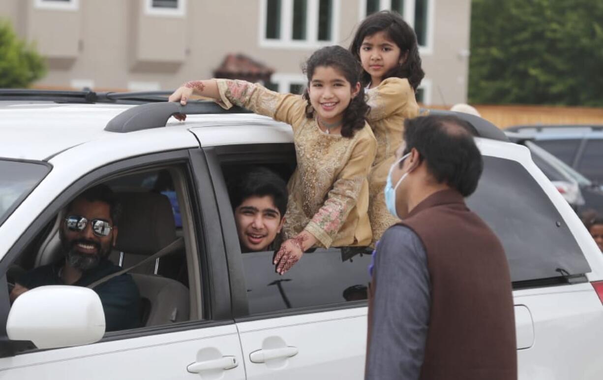 A family looks out from their vehicle during an Eid al-Fitr drive through celebration outside a closed mosque in Plano, Texas, Sunday, May 24, 2020. Many Muslims in America are navigating balancing religious and social rituals with concerns over the virus as they look for ways to capture the Eid spirit this weekend.