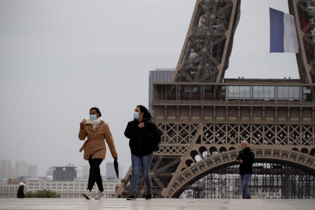 People walk near the Eiffel Tower, in Paris, Monday, May 11, 2020. The French began leaving their homes and apartments for the first time in two months without permission slips as the country cautiously lifted its lockdown. Clothing stores, coiffures and other businesses large and small were reopening on Monday with strict precautions to keep the coronavirus at bay.