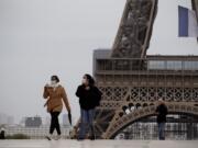 People walk near the Eiffel Tower, in Paris, Monday, May 11, 2020. The French began leaving their homes and apartments for the first time in two months without permission slips as the country cautiously lifted its lockdown. Clothing stores, coiffures and other businesses large and small were reopening on Monday with strict precautions to keep the coronavirus at bay.