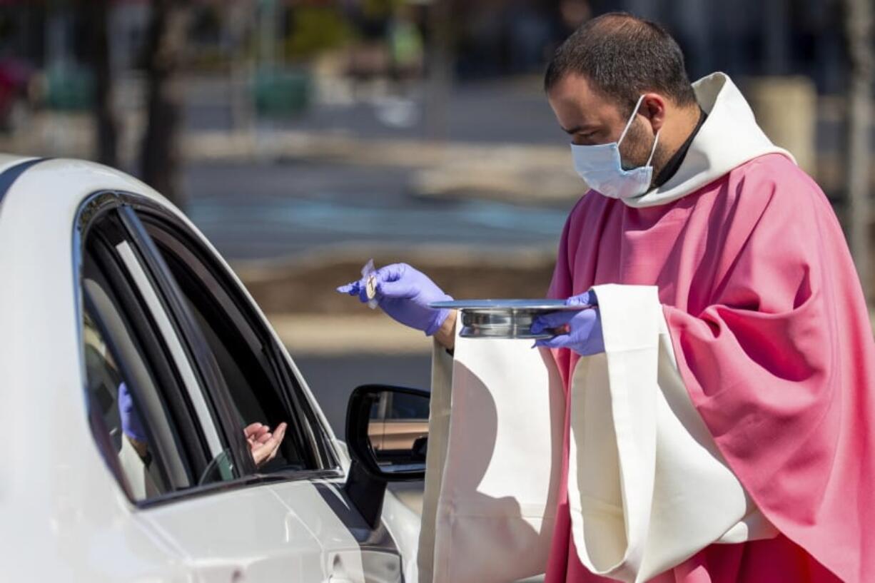 The Rev. William A. Mentz, pastor of the Scranton, Pa.-based St. Francis and Clare Progressive Catholic Church, wears a mask and gloves March 22 while distributing prepackaged communion to the faithful attending Mass while sitting in their cars in the parking lot of a shopping center in Moosic, Pa.