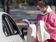 The Rev. William A. Mentz, pastor of the Scranton, Pa.-based St. Francis and Clare Progressive Catholic Church, wears a mask and gloves March 22 while distributing prepackaged communion to the faithful attending Mass while sitting in their cars in the parking lot of a shopping center in Moosic, Pa.