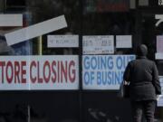 A woman looks at signs at a store closed due to COVID-19 in Niles, Ill., Wednesday, May 13, 2020. (AP Photo/Nam Y.