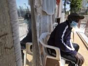 In this photo taken on Monday, April 27, 2020, a man sits outside an house where 46 men, from Nigeria and Ghana live in Castel Volturno, near Naples, Southern Italy. The house has no running water, the dilapidated electrical system doesn&#039;t reach many rooms that are in the dark. They are known as &quot;the invisibles,&quot; the undocumented African migrants who, even before the coronavirus outbreak plunged Italy into crisis, barely scraped by as day laborers, prostitutes and seasonal farm hands. Locked down for two months in their overcrowded apartments, their hand-to-mouth existence has grown even more precarious with no work, no food and no hope.