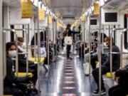 Commuters sit in the subway in Milan, Italy, Monday, May 4, 2020.  Marks on the floor show the correct distance to be kept. Italy began stirring again Monday after a two-month coronavirus shutdown, with 4.4 million Italians able to return to work and restrictions on movement eased in the first European country to lock down in a bid to stem COVID-19 infections.