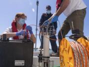 In this picture taken on Thursday, May 21, 2020, Italian Lazio region&#039;s environmental agency biologists Salvatore De Bonis, right, and Valentina Amorosi show how they perform tests on sea water during an interview with The Associated Press on a Coast Guard boat off Fiumicino, near Rome.