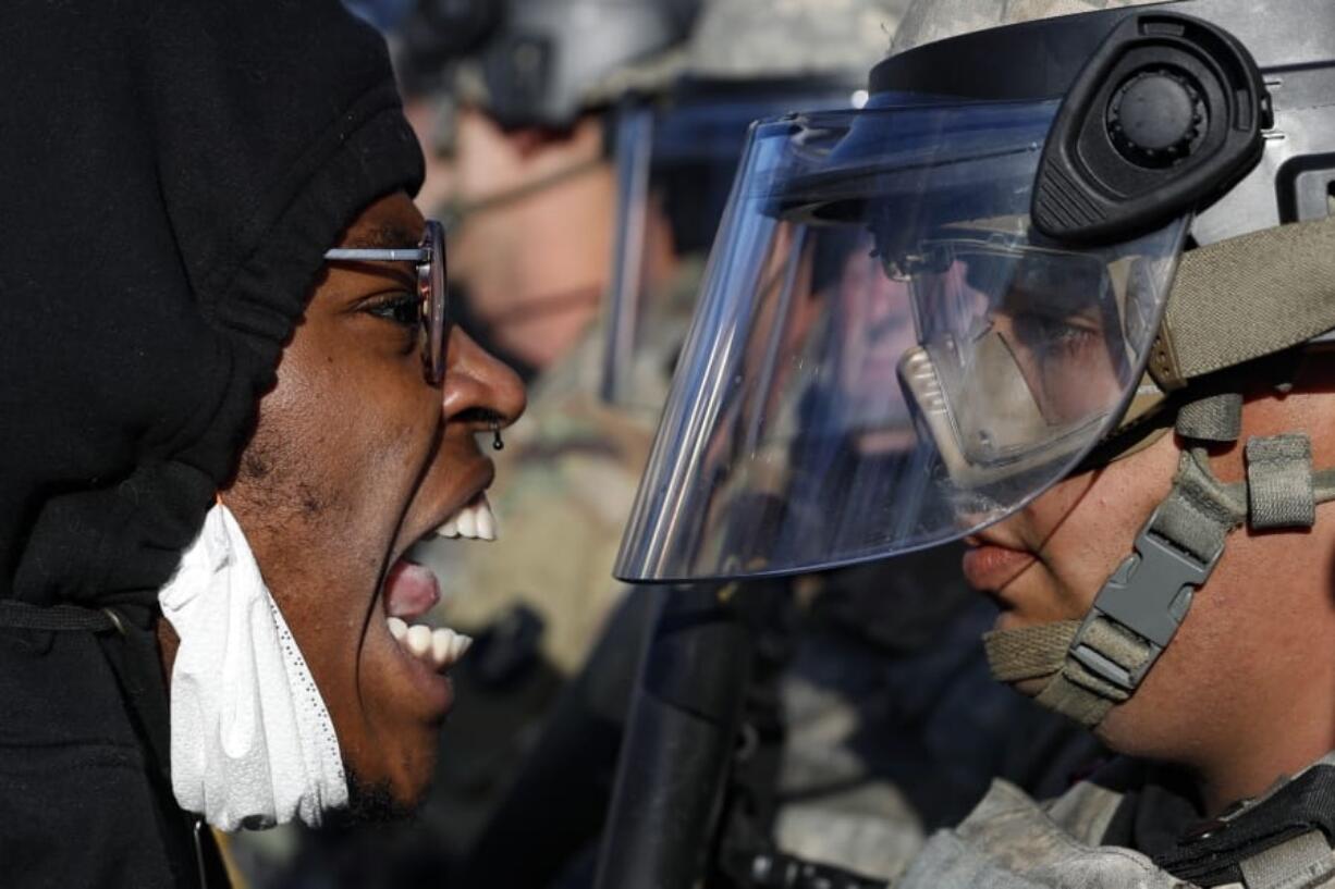 Protesters and National Guardsmen face off on East Lake Street, Friday, May 29, 2020, in St. Paul, Minn.  The massive protests sweeping across U.S. cities following the police killing of a black man in Minnesota have elevated fears of a new surge in cases of the coronavirus. Images showing thousands of screaming, unmasked protesters have sent shudders through the health community, who worry their calls for social distancing during the demonstrations are unlikely to be heard.