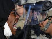 Protesters and National Guardsmen face off on East Lake Street, Friday, May 29, 2020, in St. Paul, Minn.  The massive protests sweeping across U.S. cities following the police killing of a black man in Minnesota have elevated fears of a new surge in cases of the coronavirus. Images showing thousands of screaming, unmasked protesters have sent shudders through the health community, who worry their calls for social distancing during the demonstrations are unlikely to be heard.