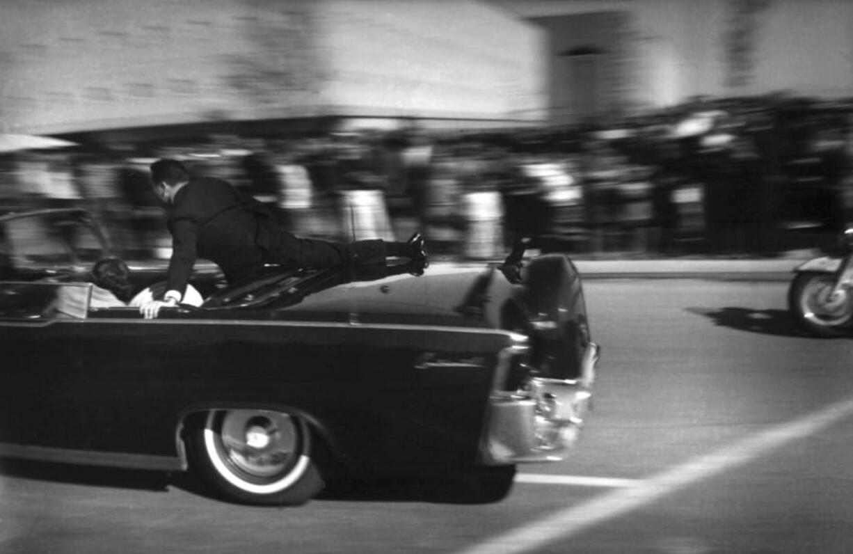 FILE - In this Nov. 22, 1963 file photo, the limousine carrying mortally wounded President John F. Kennedy races toward the hospital seconds after he was shot in Dallas. Secret Service agent Clinton Hill is riding on the back of the car, Nellie Connally, wife of Texas Gov. John Connally, bends over her wounded husband, and first lady Jacqueline Kennedy leans over the president.