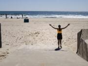 A woman walks on the beach during the coronavirus pandemic in Belmar, N.J., Saturday, May 2, 2020.