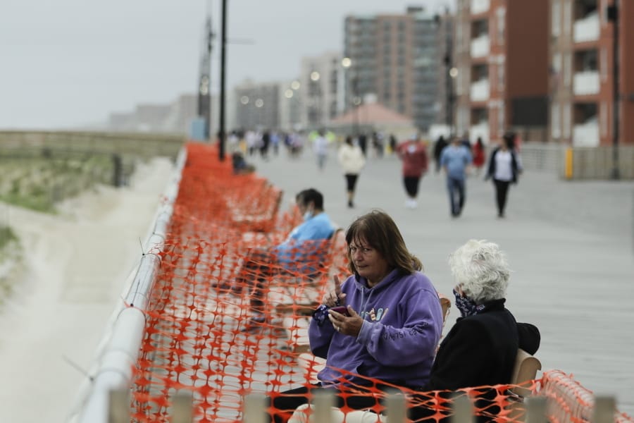 People engage in social distancing on the boardwalk during the coronavirus pandemic Friday, May 22, 2020, in Long Beach, N.Y.