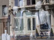 A woman sitting on a stoop reading a book in the sun is seen reflected by a closed clothing store&#039;s window on West Broadway, Thursday, May 7, 2020, in the SoHo neighborhood of the Manhattan borough in New York. The U.S. government is poised to report the worst set of job numbers since record-keeping began in 1948, a stunning snapshot of the toll the coronavirus has taken on a now-shattered economy.