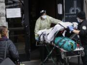 FILE- In this April 17, 2020, file photo, a patient is wheeled into Cobble Hill Health Center by emergency medical workers in the Brooklyn borough of New York. On Thursday, April 23, 2020, New York Gov. Andrew Cuomo said that nursing homes in New York must immediately report how they have complied with regulations for resident care during the coronavirus, and non-compliant facilities could face hefty fines or lose their licenses.