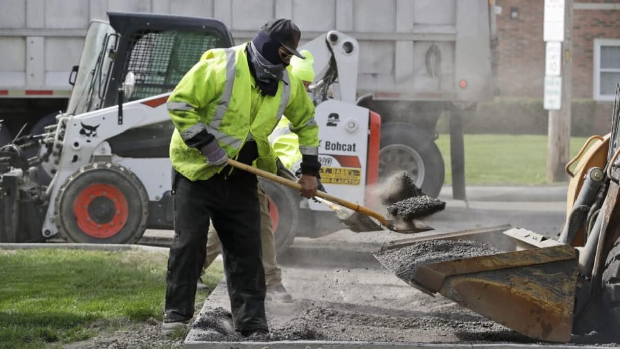 FILE - In this May 6, 2020 file photo, Jarrett Barth, who works for Dagg&#039;s Asphalt &amp; Sealcoating, shovels gravel into a backhoe bucket in Lyndhurst, Ohio. U.S. productivity fell a sharp 2.5% in the first three months of this year as labor costs jumped 4.8%.