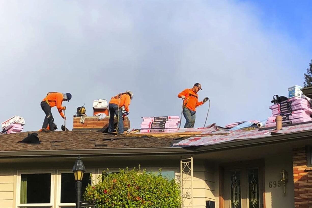 Roofers work on a home in Salem, Ore., on Tuesday. Oregon Gov. Kate Brown has allowed construction to continue under her stay-home order.