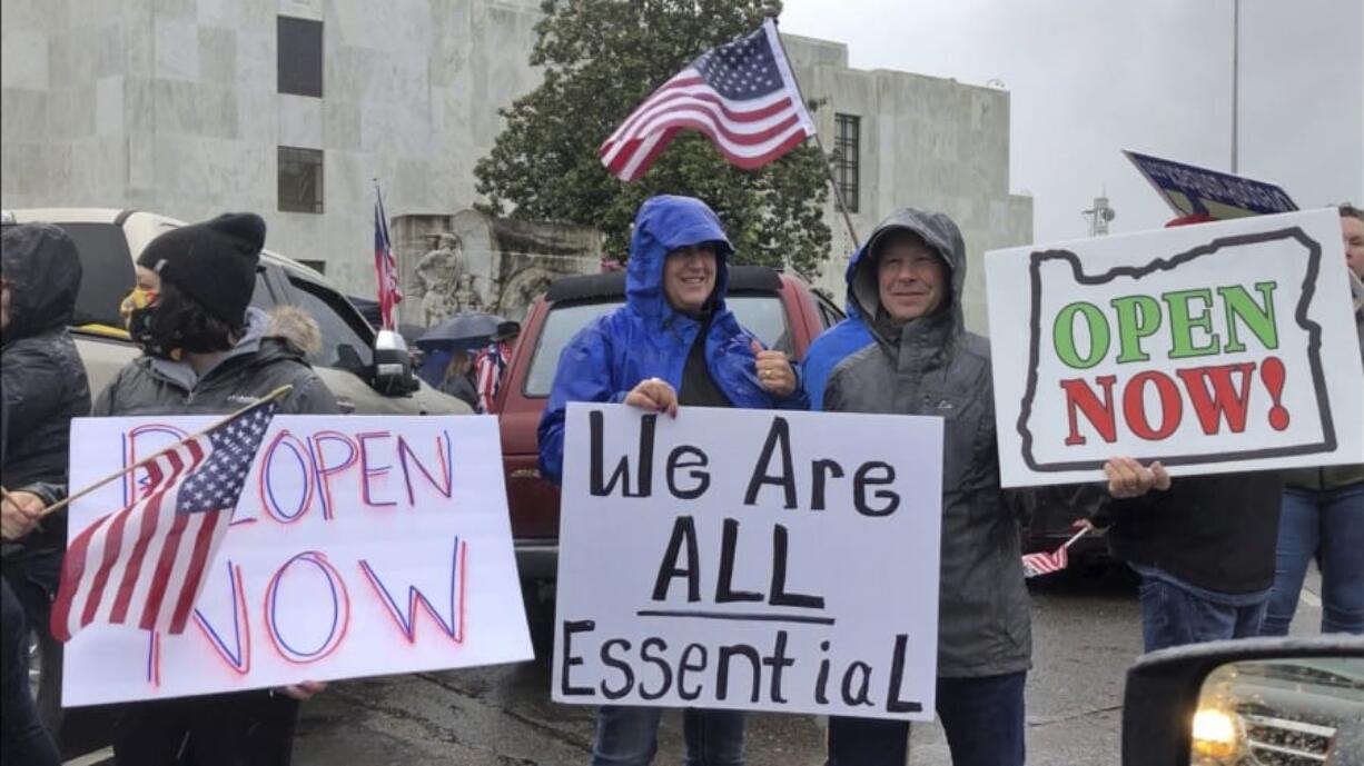 People hold signs protesting Oregon Gov. Kate Brown&#039;s executive order that shut down much of the state&#039;s economy and imposed social distancing, in her effort to stem the spread of the coronavirus, rally outside the Oregon State Capitol in Salem, Ore., on Saturday, May 2, 2020.