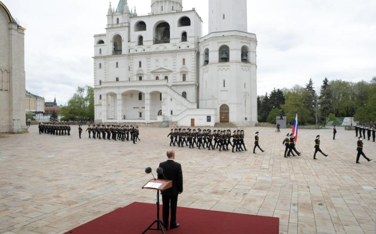 Russian President Vladimir Putin, back to a camera, watches the honour guard of the Presidential Regiment march on Cathedral Square in the Kremlin marking the 75th anniversary of the Nazi defeat in World War II in Moscow, Russia, Saturday, May 9, 2020.