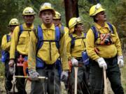 FILE - IN this Aug. 18, 2017, file photo, exhaustion reads on the face of a firefighter from Noorvik, Alaska, while he and his team watch for spot fires that threaten to jump the line on the Lolo Peak fire, in Missoula, Mont. A federal risk assessment says wildland firefighters could see widespread outbreaks of COVID-19 at large U.S. fire camps this summer, and the problem is likely to compound the longer fire season lasts. The draft risk assessment created by the U.S. Forest Service predicts that even in a best-case scenario -- with firefighters following social distancing protocols and plenty of tests and equipment available -- that nearly two dozen people could be infected by the virus while working at a camp like the one used for the Lolo Peak fire.