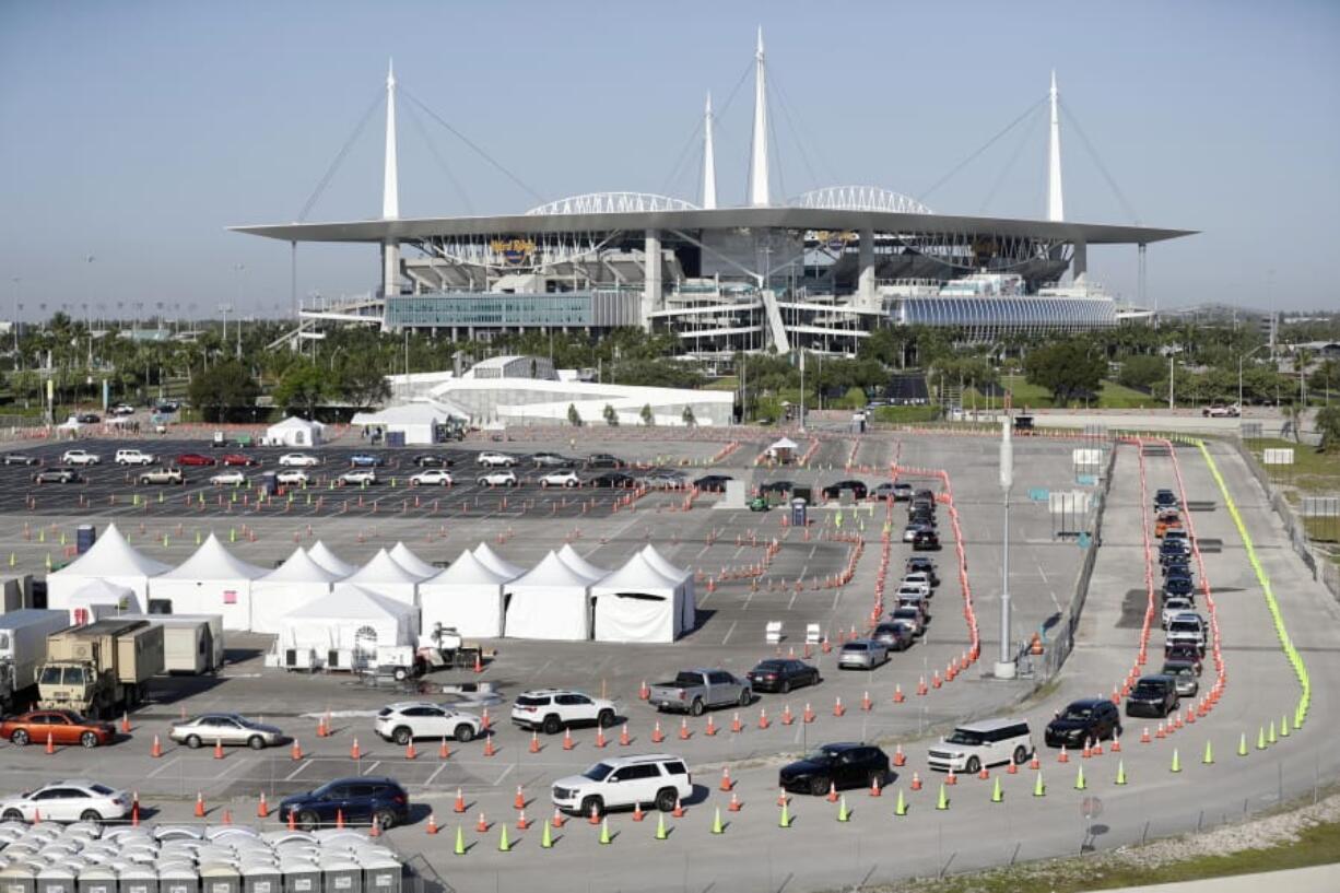 Cars line up at a drive-thru coronavirus testing site in front of Hard Rock Stadium in Miami Gardens, Fla. Nobody can say with precise certainty how many coronavirus tests that the NBA, NHL and Major League Baseball would need before those leagues can resume playing games.