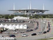 Cars line up at a drive-thru coronavirus testing site in front of Hard Rock Stadium in Miami Gardens, Fla. Nobody can say with precise certainty how many coronavirus tests that the NBA, NHL and Major League Baseball would need before those leagues can resume playing games.