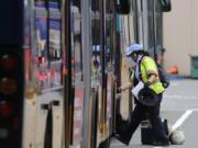 A King County Metro bus driver wipes down a handrail before stepping onto a bus Monday, May 11, 2020, in Seattle. The coronavirus pandemic has plunged Puget Sound-area transit agencies into crisis-planning mode, as ridership and revenue has plunged and predictions that people will not be returning to buses and trains in large numbers anytime soon. The Seattle Times reports that beyond the immediate health crisis, the pandemic threatens to undo years of transit growth and plunge local transit systems into a financial setback worse than the Great Recession in the late 2000s.