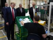 President Donald Trump participates in a tour of a Honeywell International plant that manufactures personal protective equipment, Tuesday, May 5, 2020, in Phoenix, with Tony Stallings, vice president of Integrated Supply Chain at Honeywell, right and White House chief of staff Mark Meadows.