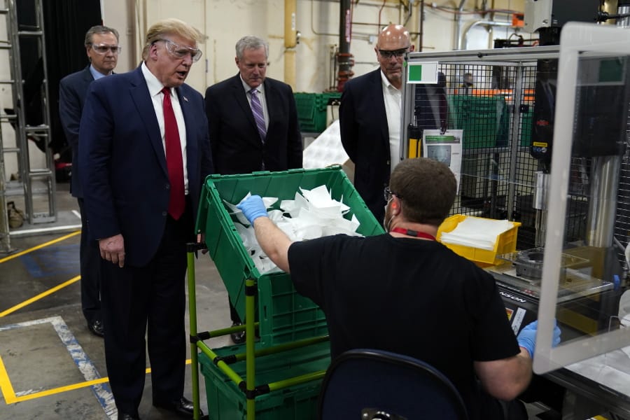 President Donald Trump participates in a tour of a Honeywell International plant that manufactures personal protective equipment, Tuesday, May 5, 2020, in Phoenix, with Tony Stallings, vice president of Integrated Supply Chain at Honeywell, right and White House chief of staff Mark Meadows.