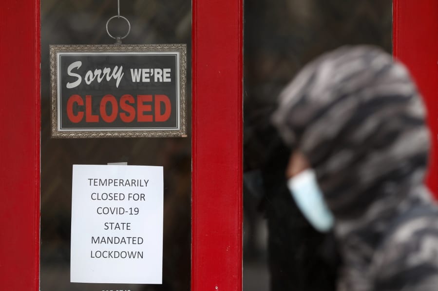 FILE - In this May 7, 2020 file photo, a pedestrian walks by The Framing Gallery, closed due to the COVID-19 pandemic, in Grosse Pointe, Mich. The U.S. unemployment rate hit 14.7% in April, the highest rate since the Great Depression, as 20.5 million jobs vanished in the worst monthly loss on record. The figures are stark evidence of the damage the coronavirus has done to a now-shattered economy..