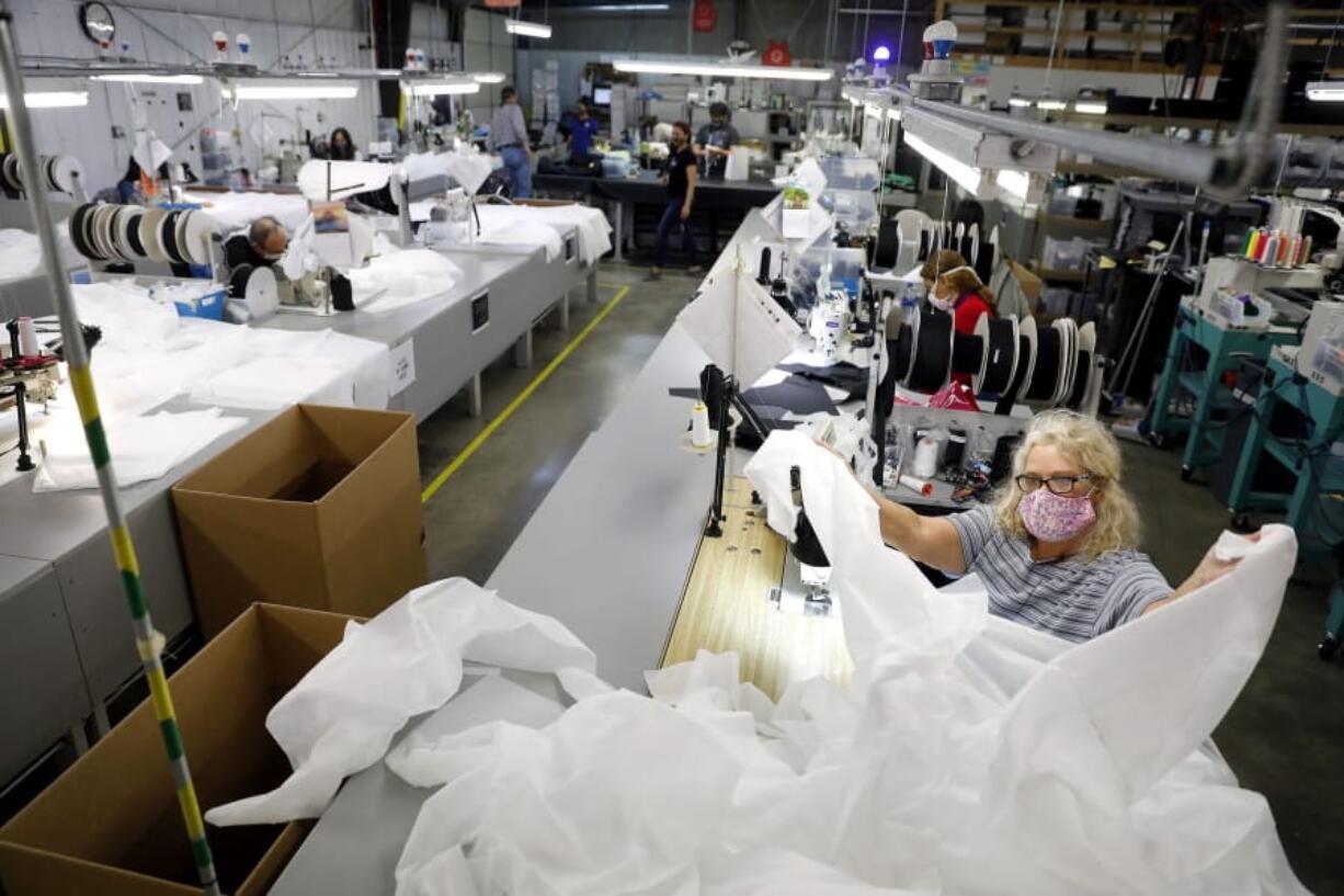 Angie Moorefield unfolds material to begin sewing a disposable gown at Burlington Medical in Newport News Wednesday, May 6, 2020. The manufacturing business recently shifted from producing radiation protection gear for medical facilities to in-demand personal protective equipment such as masks, gowns and plastic face shields.