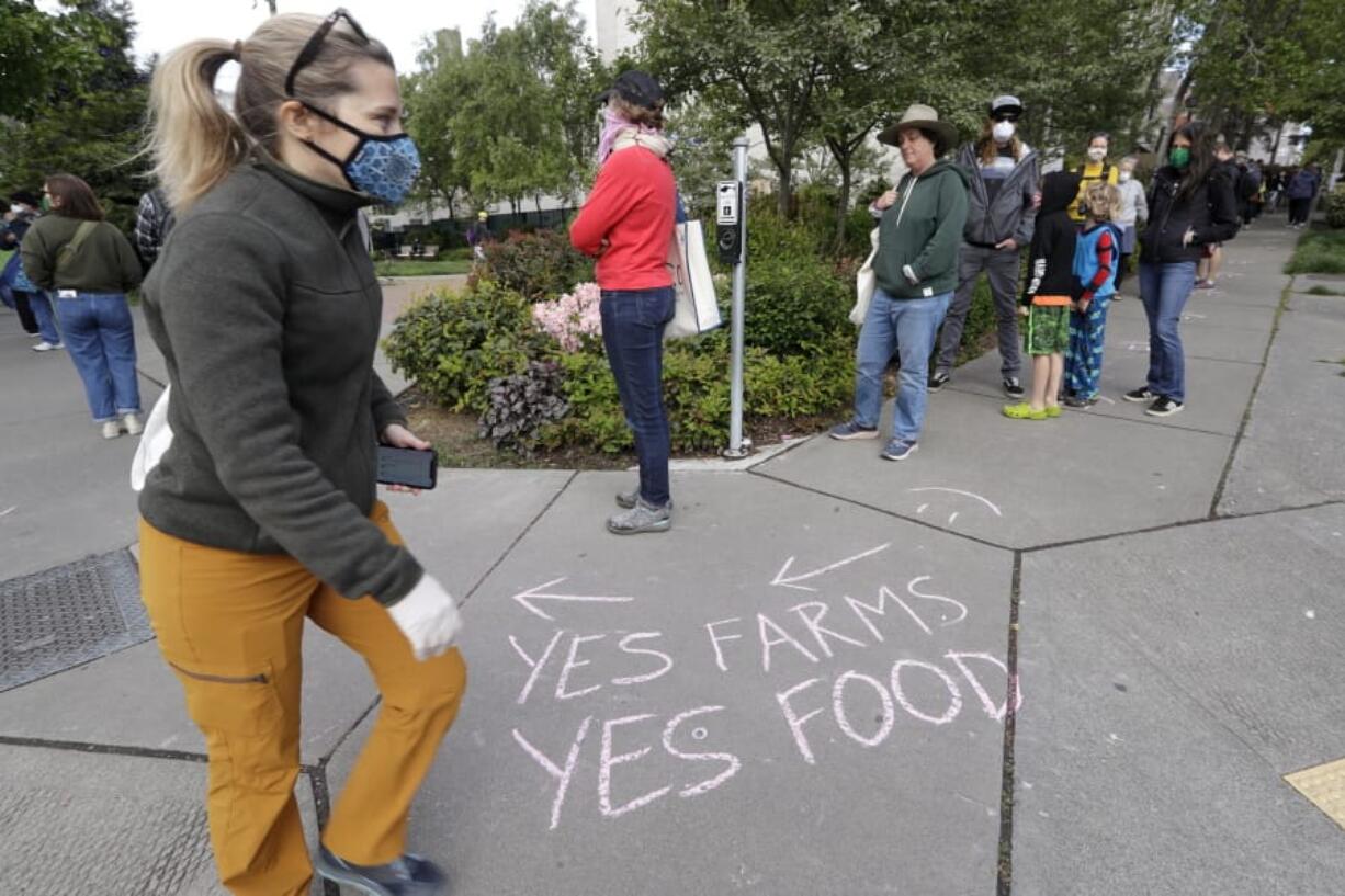 A line of customers snaking around the block waits to enter the West Seattle Farmers Market during its first opening in nearly two months because of the coronavirus outbreak Sunday, May 3, 2020, in Seattle. Farmers markets in Seattle were initially closed, but are reopening with guidelines that include fewer vendors allowed, a limited number of customers with a single direction of movement, additional hand washing and sanitizing stations and signs and markings urging customers to maintain distance from each other.