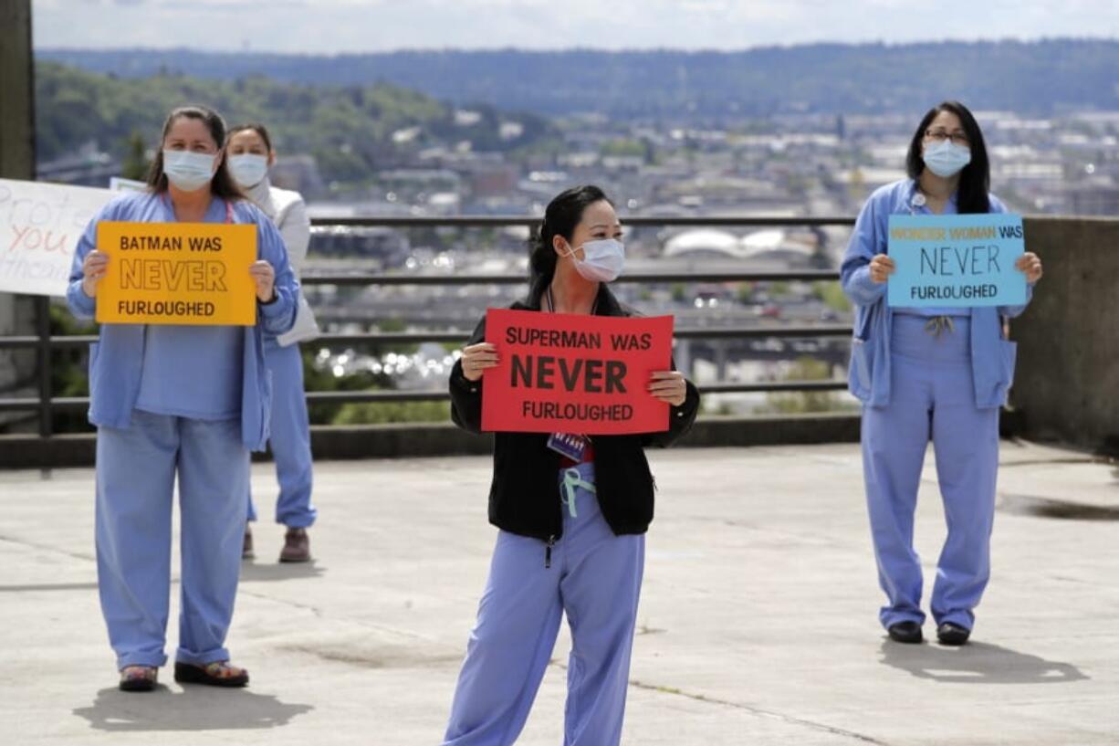 Health care workers Mechelle Cannon, left, Chiow Saechao and Gina Tualla stand in protest with other staff at Harborview Medical Center, a part of UW Medicine, during a noon hour break in a demonstration asking management to do more to protect staff, patients and the public amid the COVID-19 pandemic, Thursday, May 14, 2020, in Seattle. Protest organizers said UW Medicine has failed to fully implement public health guidance designed to flatten the curve, including proper notification to staff regarding exposure, the installation of sneeze guards to protect staff and the public, and the distribution of personal protective equipment, and has refused to extend agreements with unions that provide economic protections for employees.