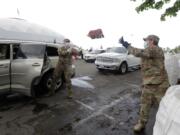 Members of the Washington National Guard toss a bag of potatoes as they load a waiting car, Thursday, May 14, 2020, during the free distribution of 200,000 pounds of potatoes provided by the Washington State Potato Commission in Tacoma, Wash. Most of the potatoes were donated by farmers across the state who have not been able to sell to their regular restaurant customers due to the coronavirus pandemic. (AP Photo/Ted S.